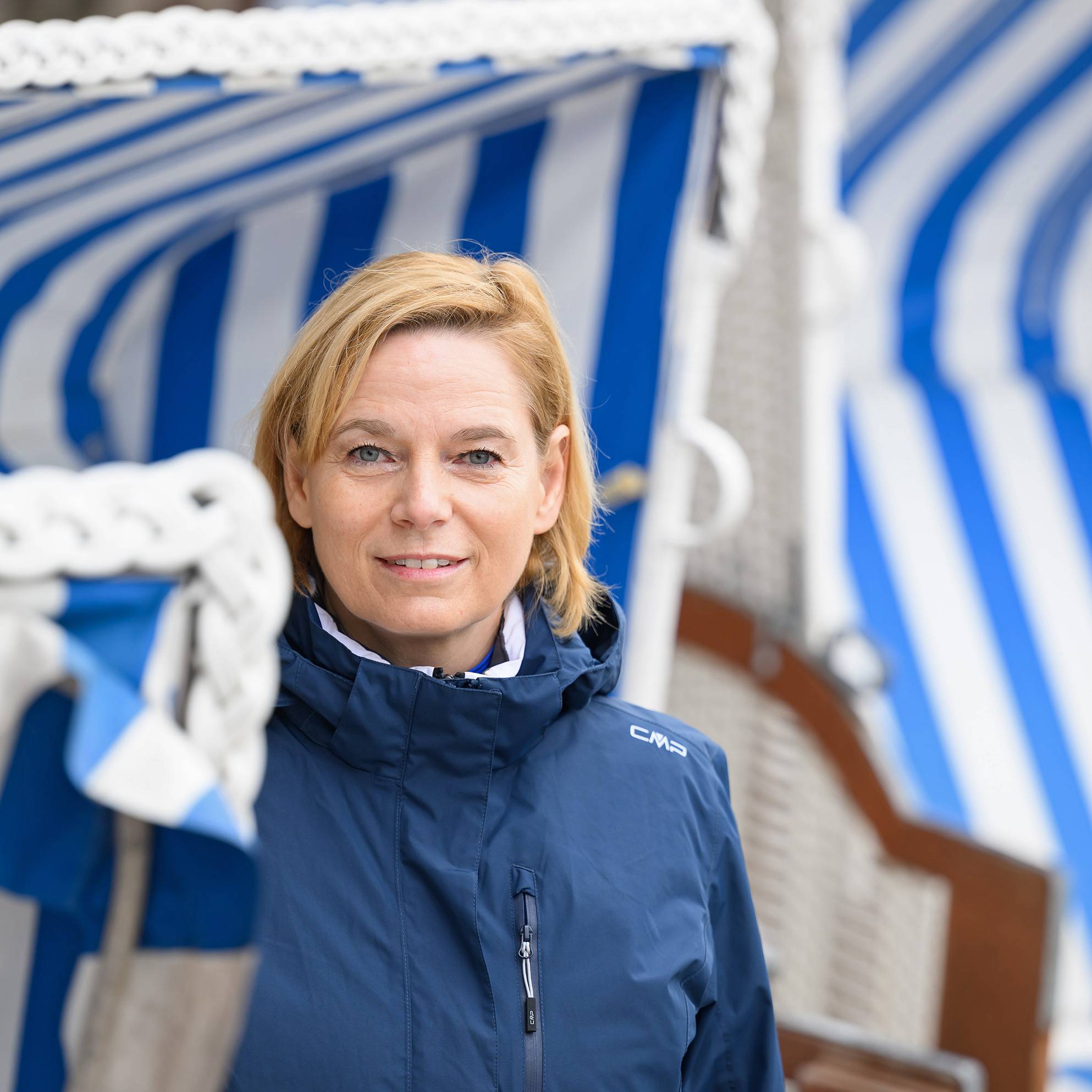 Die Rehabilitandin Susanne Kaucher sitzt in einem Strandkorb und schaut leicht lächelnd in die Kamera.