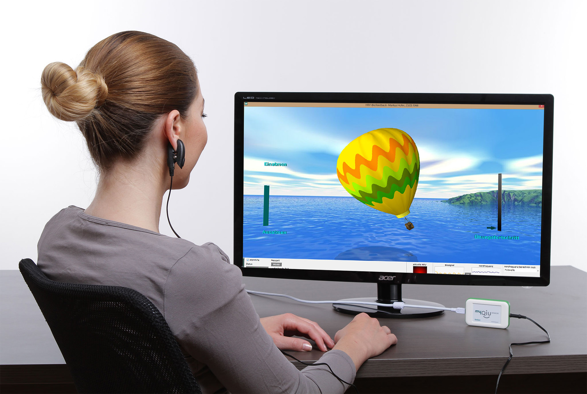 Frau sitzt vor Computerbildschirm und wendet ein Biofeedback-Programm an