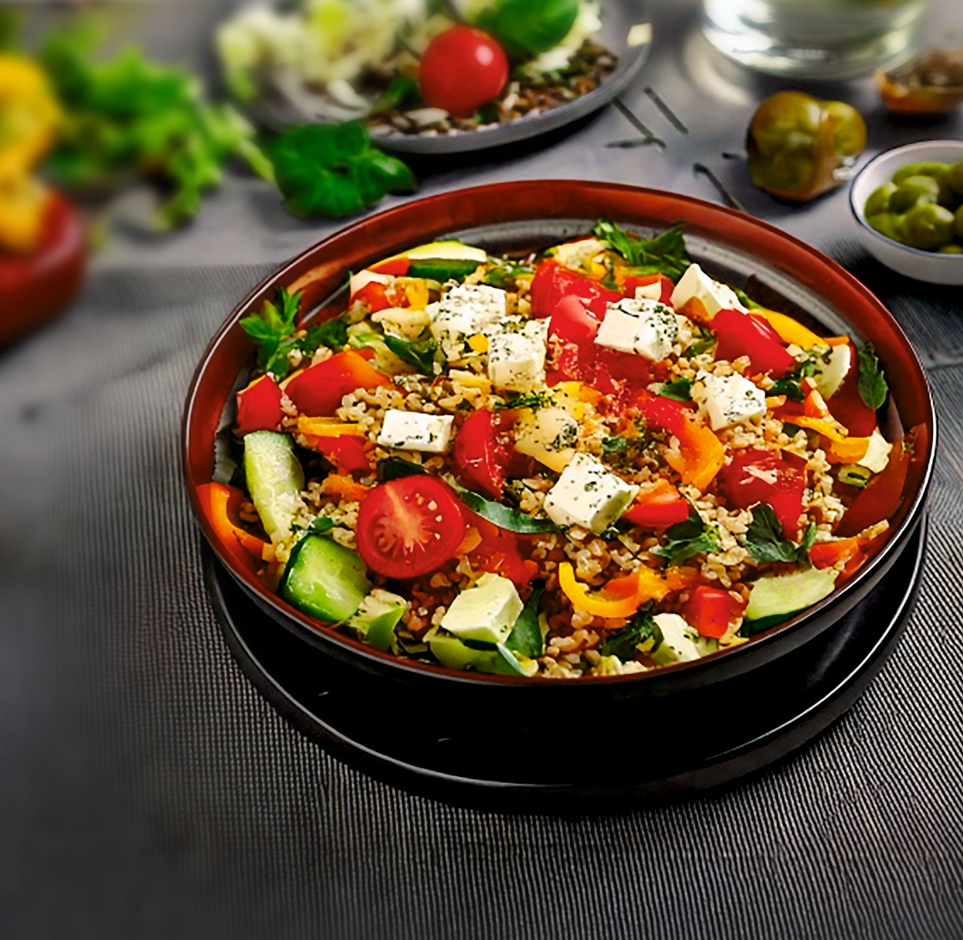 Bunter Bulgursalat mit Paprika, Gurken, Tomaten und Feta, serviert in einer Schale – frisch, gesund und mediterran gewürzt.
